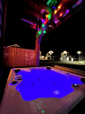 A hot tub with a blue light, surrounded by a wooden deck and colorful lights. - Apex Mountain: Private Hot Tub near Village & Skating Loop with mountain views (Okanagan-Similkameen G)