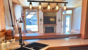 Une cuisine avec des meubles en bois, un évier à deux bacs et des luminaires suspendus.