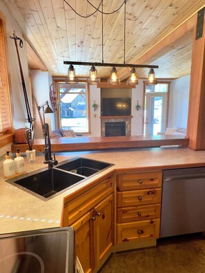 A kitchen with wooden cabinets, a double sink, and pendant lighting.