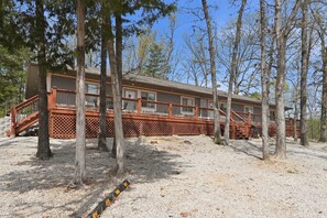 A cabin with a deck, surrounded by trees. - Quail Cove Dogwood Lakefront Boat Slip Optional (Shell Knob)