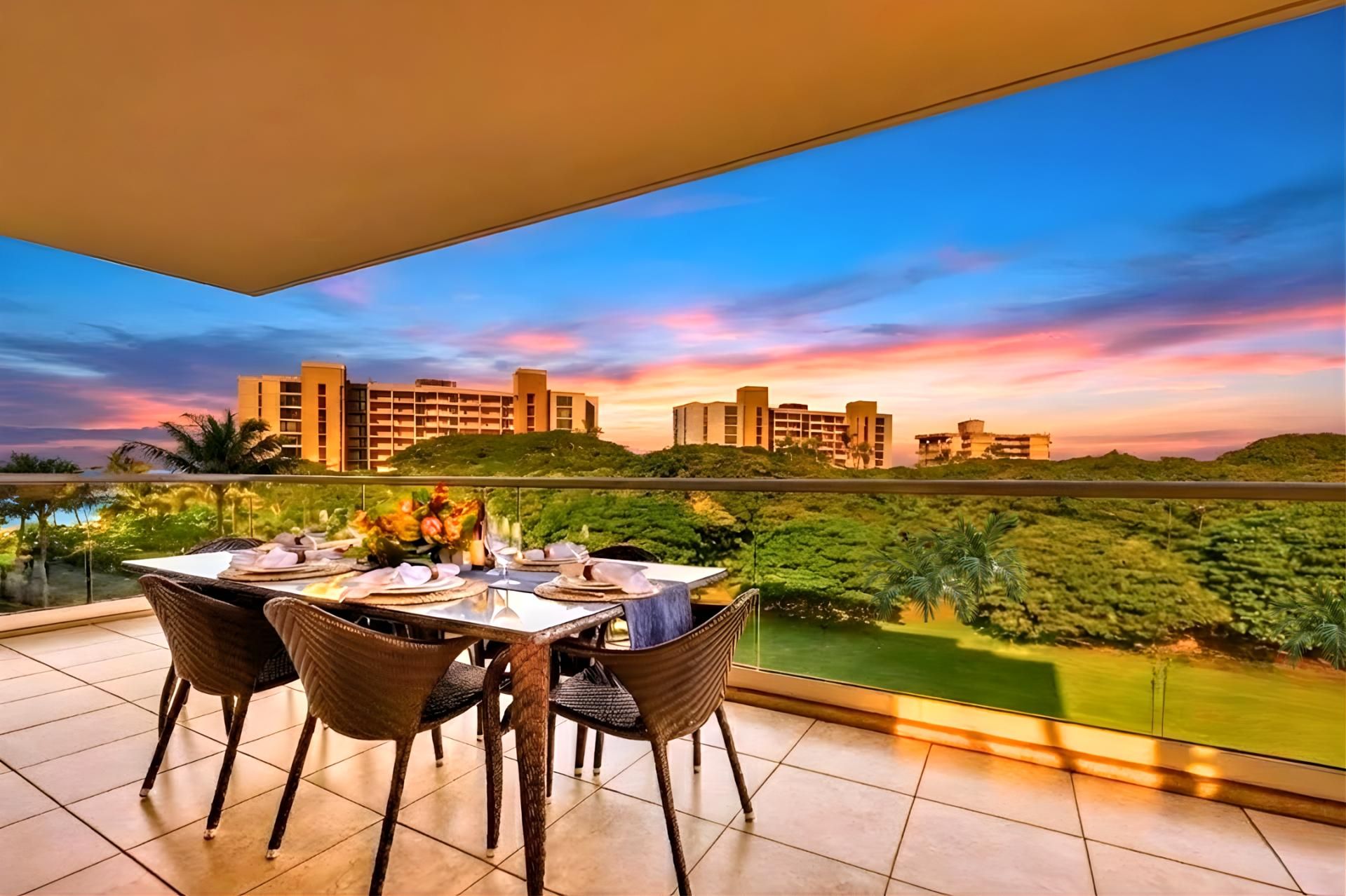 A balcony with a table set for dining, overlooking a cityscape and lush greenery.