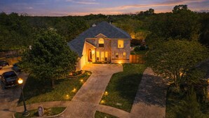 A two-story house with a brick exterior, a driveway, and a well-maintained lawn.
