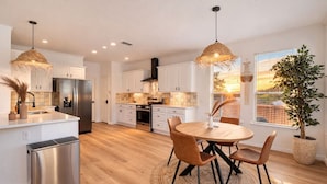 A modern kitchen with white cabinetry, stainless steel appliances, and a round dining table with chairs.
