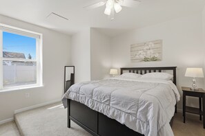 A bedroom with a bed, two bedside tables, a ceiling fan, a window, and a wall-mounted artwork. - Downtown Rochester Gem (Rochester)