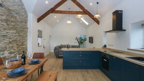 Un'ampia cucina con un'isola grande, travi in legno e luci a sospensione.