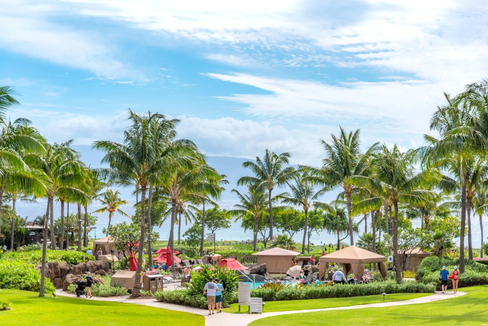 Ein Resort mit Palmen, einem Poolbereich und blauem Himmel.