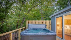 A hot tub on a wooden deck with a glass door leading to a room. - Cozy cabin w/ hot tub near Beavers Bend (Broken Bow)