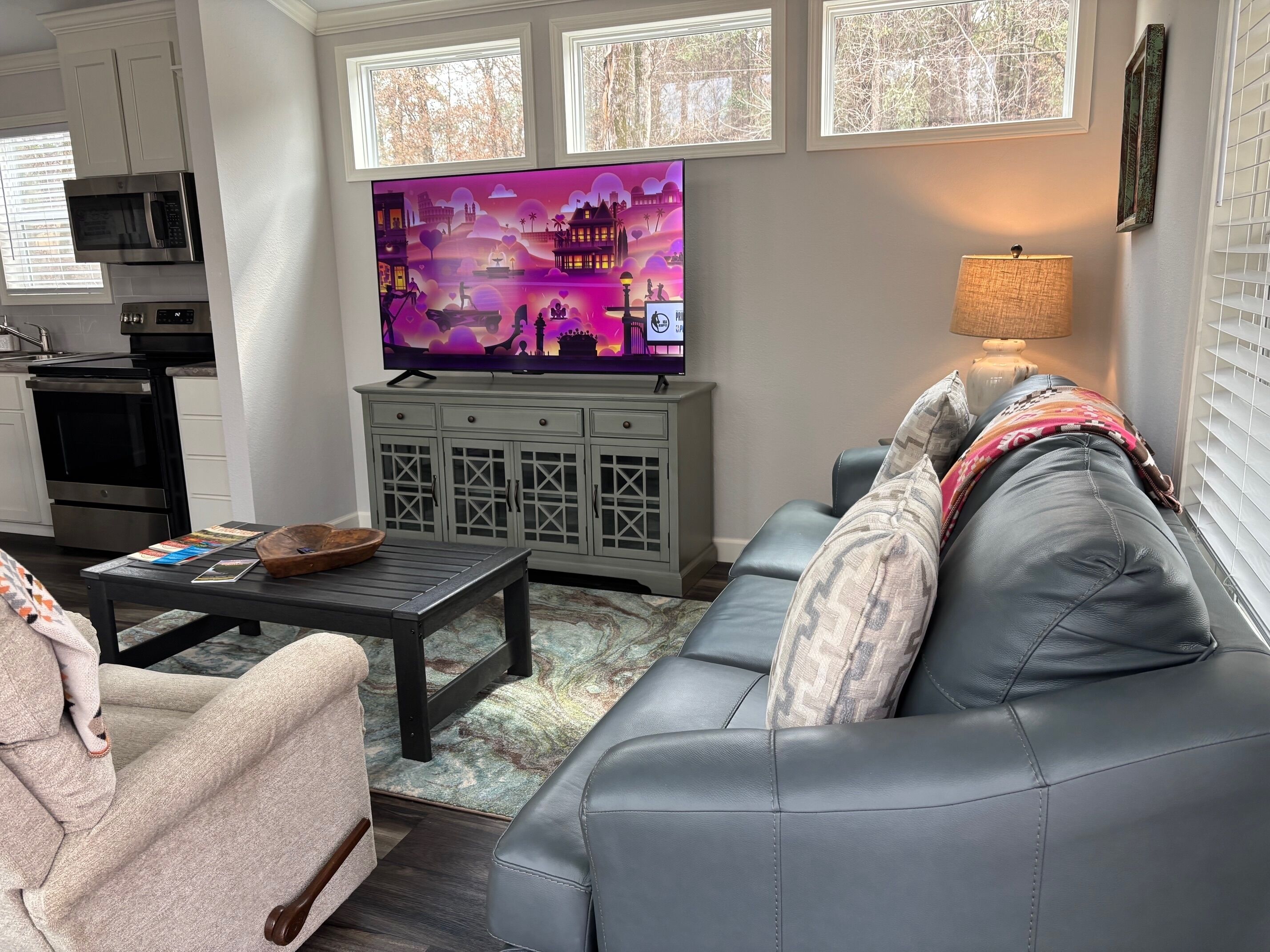 A living room with a television, sofa, coffee table, and kitchen area.