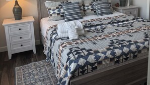 Quarto com cama, mesas de cabeceira, tapete e uma placa na parede.