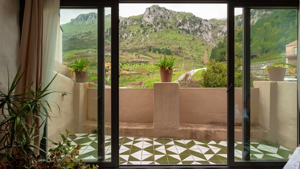 A balcony with a view of a mountainous landscape, potted plants, and a tiled floor. - Authentic Sicilian house in village 20 km from the sea (Gratteri)