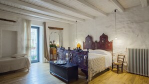 A bedroom with a wooden bed, a dresser, a chair, a radiator, and a window with curtains. - Authentic Sicilian house in village 20 km from the sea (Gratteri)