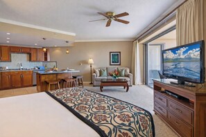A hotel room with a bed, a TV, a dining area, a ceiling fan, and a large window. - Honua Kai | Ocean View 2 BR, Sleeps 8 | Car Incl. w/ 6+ Nights | HKK ML-3896 by KBM (Lahaina)