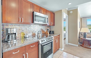 A kitchen with wooden cabinets, a stainless steel range, a microwave, and a coffee maker. - Honua Kai | Ocean View 5 BR, Sleeps 14 | Car Incl. w/ 6+ Nights | HKK ML-3906 by KBM (Lahaina)