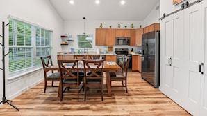 Eine moderne Küche mit Holzausstattung, einem Edelstahlkühlschrank und einem Essbereich mit einem Holztisch und Stühlen.
