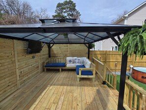 Een overdekt terras met houten banken en een glazen dak.