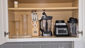 Una cucina con un mobile integrato, un frullatore, una macchina da caffè e un quadro incorniciato sul piano di lavoro.