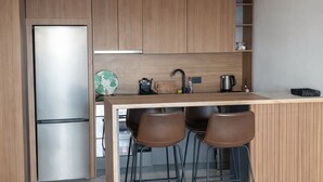 A modern kitchen with a built-in refrigerator, wooden cabinets, a bar area with stools, and a pendant light fixture. - Residance with pool ,sauna and free garrage (Budva)