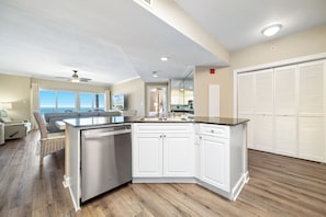 A modern kitchen with white cabinetry, a dishwasher, and a view of the ocean. - Admirals Quarters 204 | Beachfront Views | Indoor & Outdoor Pools | My Beach Getaways (Orange Beach)