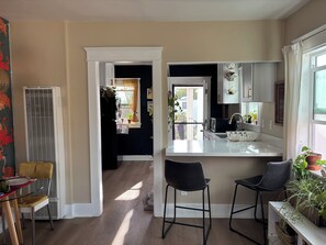 A kitchen with a central island, two bar stools, a microwave, and a sink. - Whimsical Spanish Colonial Home with Earthy Patio and Garden (Long Beach)