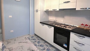 Eine Küche mit weißen Schränken, einem Gasherd und einer Uhr an der Wand.