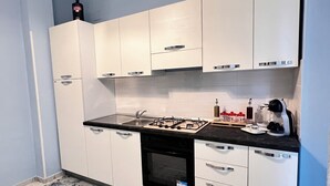 Eine moderne Küche mit weißen Schränken, einem Gasherd, einer Kaffeemaschine und einem Geschirrspüler.