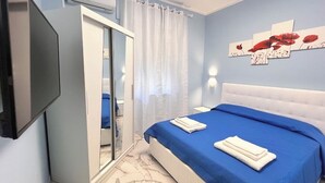 Ein Schlafzimmer mit Bett, Fernseher, Dusche und einem Bild an der Wand.