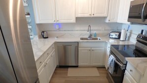 A modern kitchen with white cabinets, stainless steel appliances, and a microwave. - Charming Family Retreat Near Beach & Boardwalk, 841 Plymouth Place (Ocean City)