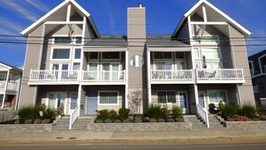 A two-story residential building with a symmetrical facade, balconies, and a central chimney. - Charming Family Retreat Near Beach & Boardwalk, 841 Plymouth Place (Ocean City)