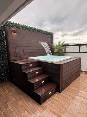 A hot tub with a wooden exterior, built-in steps, and a water feature. - Spacious 3-bedroom apartment in charming Santo Domingo Este with AC and WiFi  (Santo Domingo Este)
