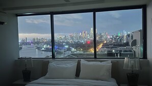 Une chambre avec une grande fenêtre donnant sur la ville.