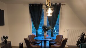 A dining area with a round table and four chairs, a small side table, a black rug, and a ceiling light fixture. - Vacation apartment Kampić "Hirsch&Heimat" (Rottweil)