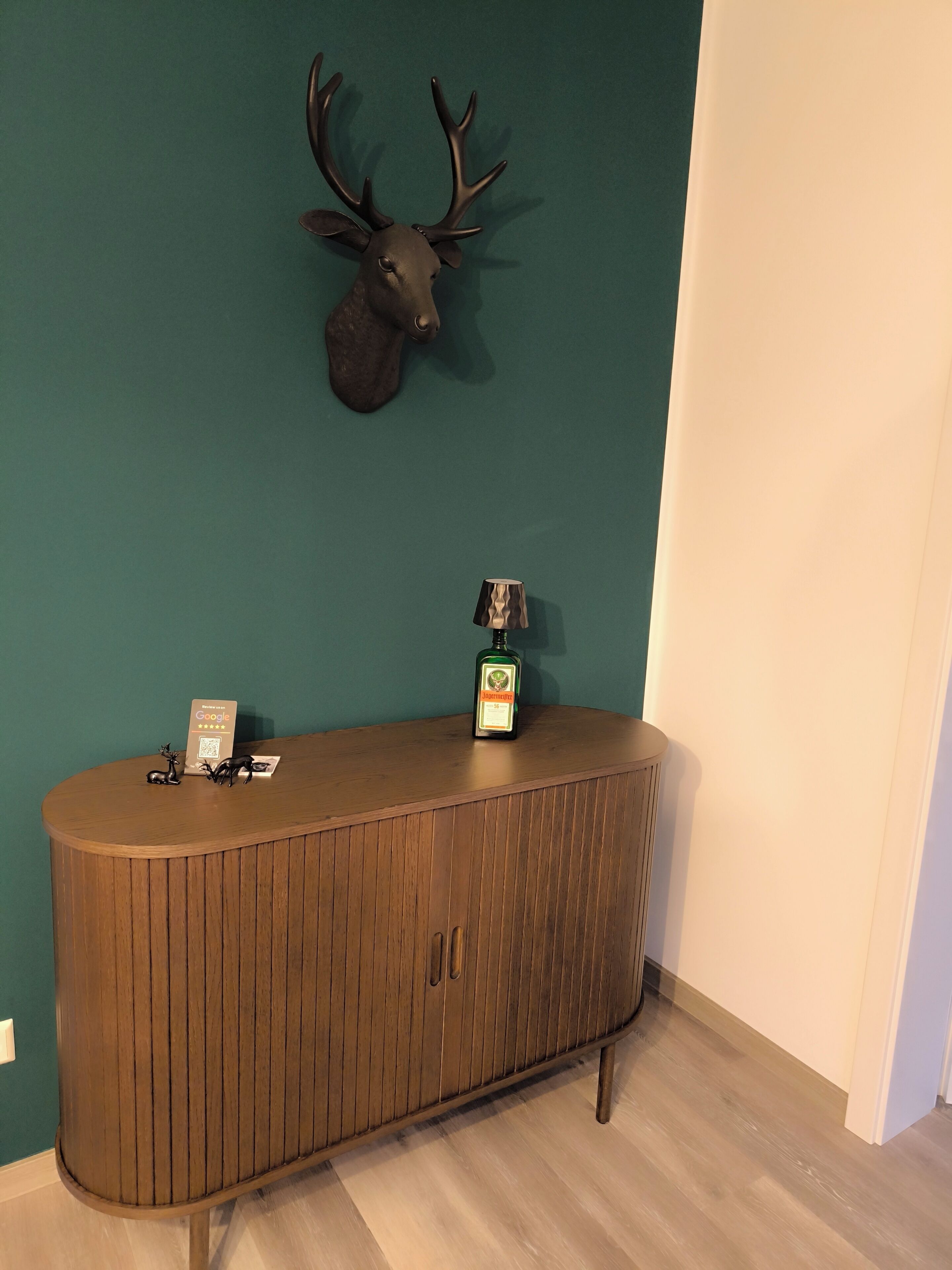 Un mostrador de recepción de madera con una cabeza de venado montada, una botella de licor y un cartel con un código QR.