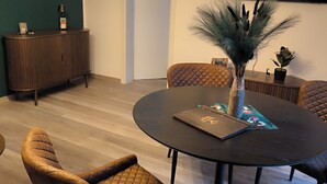 A dining area with a round table, cushioned chairs, a decorative vase, and a television mounted on the wall. - Vacation apartment Kampić "Hirsch&Heimat" (Rottweil)