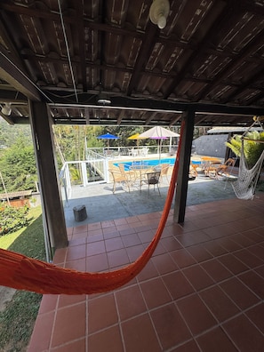 A covered outdoor area with a hammock, a pool, and outdoor furniture.