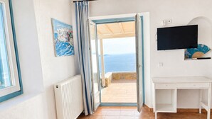 A room with a bed, a desk, a TV, a painting, and a view of the sea. - Lighthouse Villa w Private Pool & 220° Sea View (Faros Armenistis)
