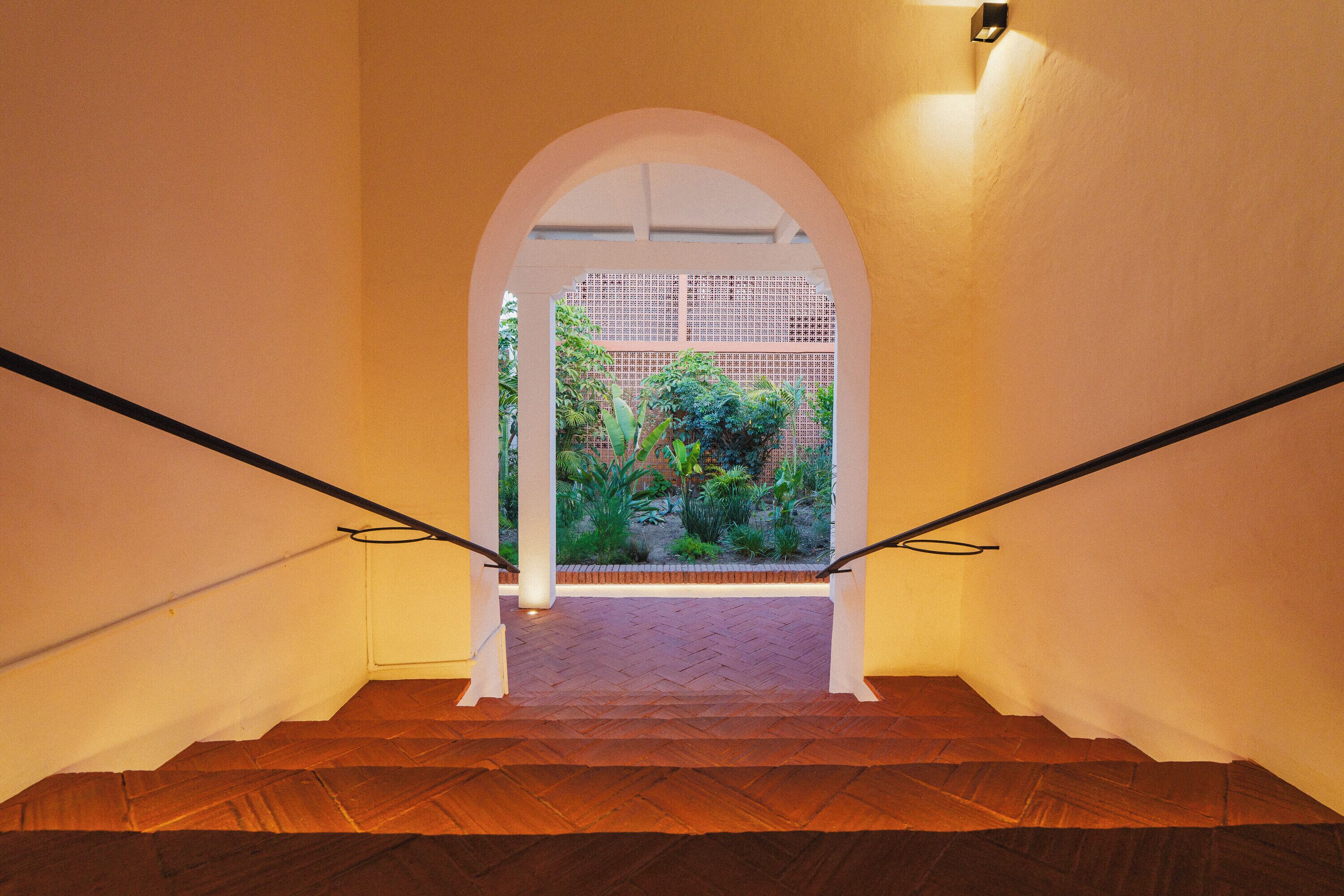 A staircase with a view of a garden through an archway.