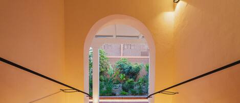 A staircase with a view of a garden through an archway.