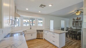 Una cocina moderna con armarios blancos, lavavajillas de acero inoxidable y encimera de mármol.