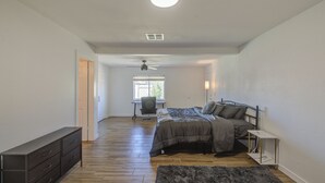 Un dormitorio con cama, escritorio, silla, cómoda y ventilador de techo.