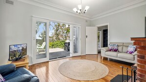 Una sala de estar con sofá, televisión, chimenea y vistas al exterior.