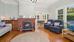 Una sala de estar con chimenea, sillones de cuero, un sofá y una televisión.