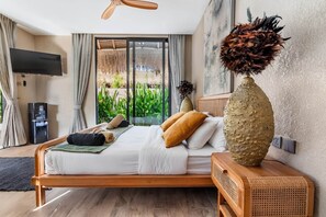 A modern bedroom with a bed, a television, a water dispenser, and a view of greenery. - Thula Lembongan Villa 3 (Lembongan)