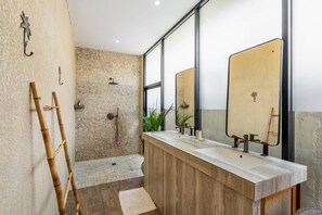 Un baño moderno con ducha, dos lavamanos, un espejo y una escalera de bambú.