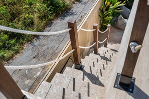 A wooden staircase with a metal handrail, leading to a higher level. - Thula Lembongan Villa 5 (Lembongan)