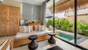 A modern bedroom with a large bed, a small table, and a view of a swimming pool. - Thula Lembongan Villa 5 (Lembongan)