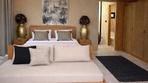 A spacious bedroom with a large bed, a ceiling fan, a modern abstract painting, and a view into another room. - Thula Lembongan Villa 5 (Lembongan)