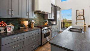 A modern kitchen with grey cabinets, a large stove, and a view of the outdoors. - 🌄 Blue Ridge Mountain Escape | Scenic Mountain Getaway, Hot Tub & Game Room (Blue Ridge)
