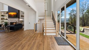 A modern interior with a staircase, a fireplace, and a view of the outdoors. - 🌄 Blue Ridge Mountain Escape | Scenic Mountain Getaway, Hot Tub & Game Room (Blue Ridge)