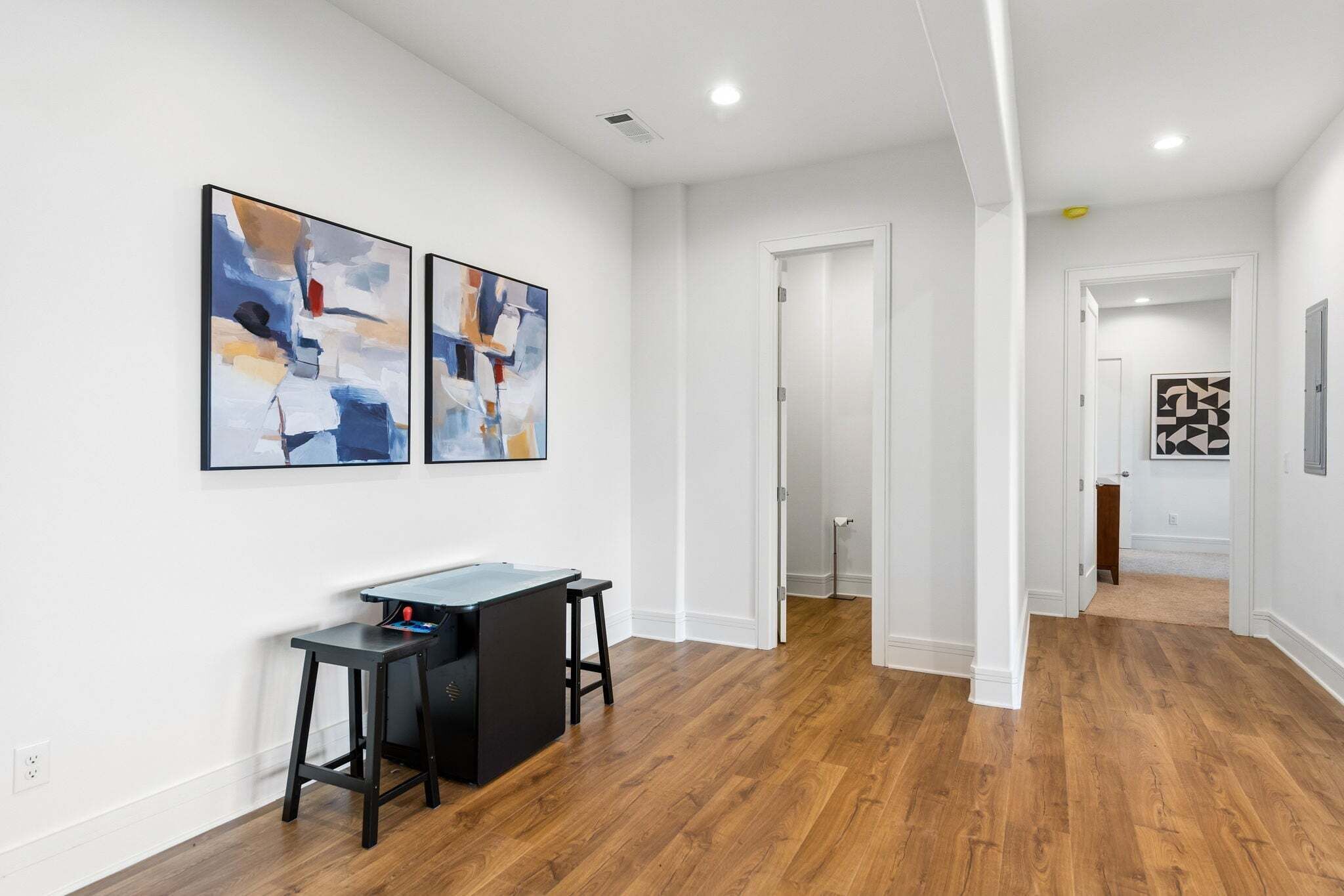 A modern interior with a desk, two abstract paintings, and hardwood flooring.