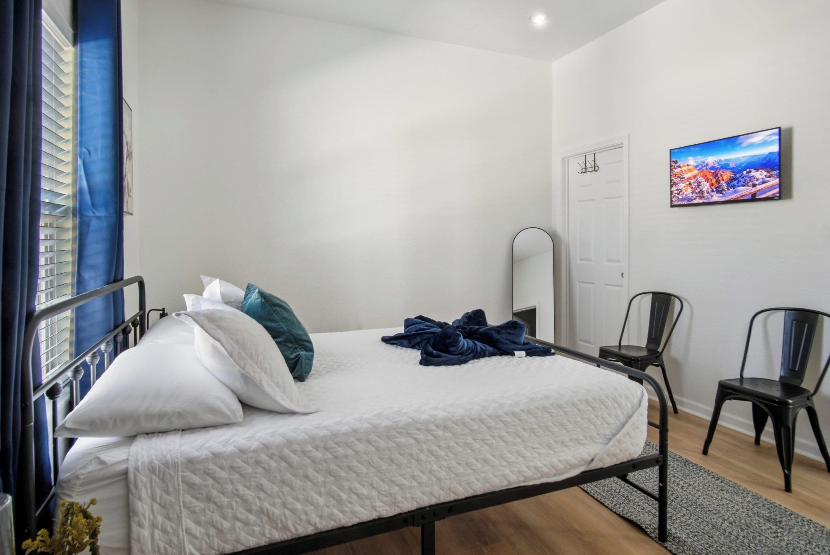 Ein Schlafzimmer mit Bett, Spiegel, Fernseher und zwei Sesseln.